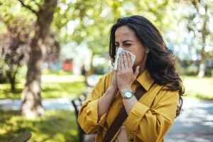 Woman blowing nose outside